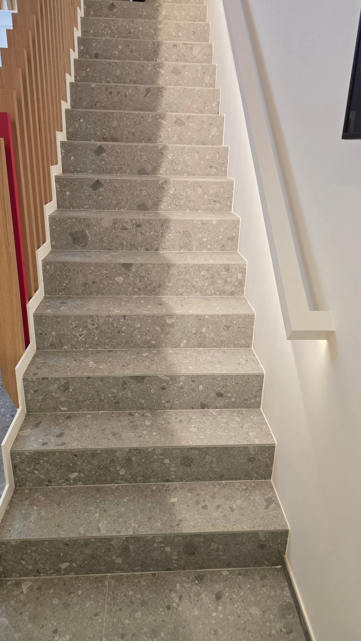 Escalier carrelé en grand format clair, marches sans cornière métallique
